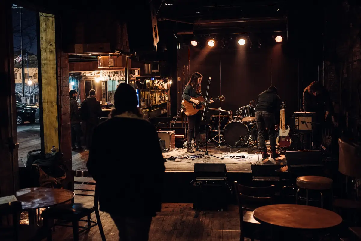 Soundcheck in un piccolo club: cantautrice con chitarra acustica al microfono e batteria sul palco