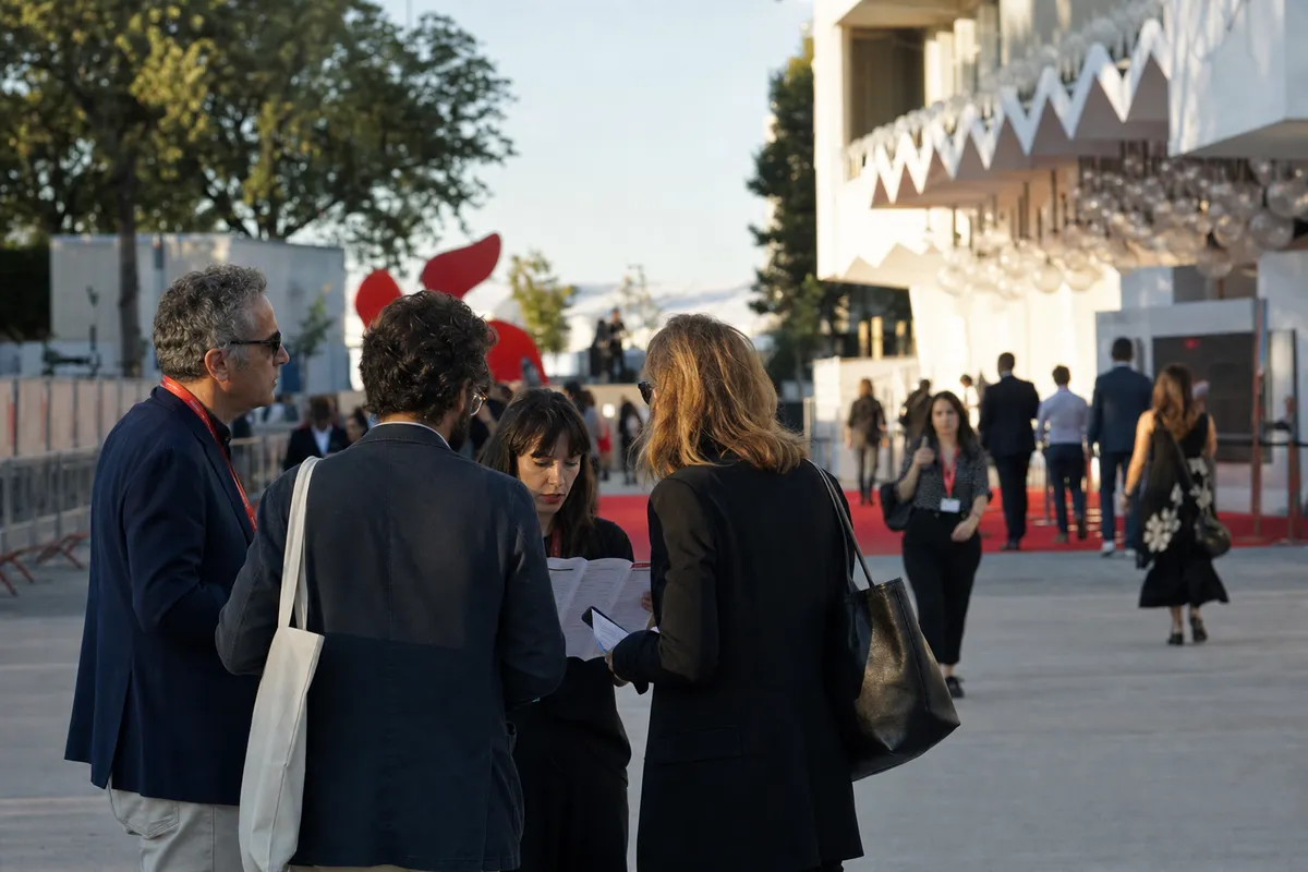Accreditati al festival discutono un programma vicino al tappeto rosso davanti a una sede cinematografica